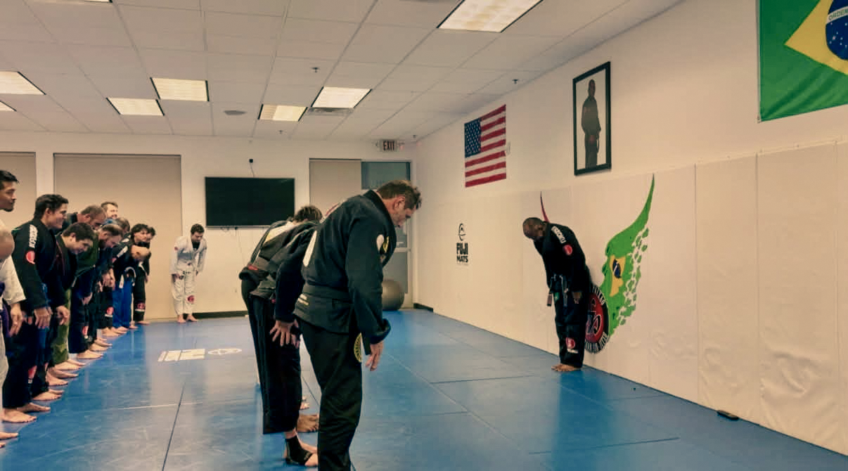 Practitioners bow together on the Academy mats