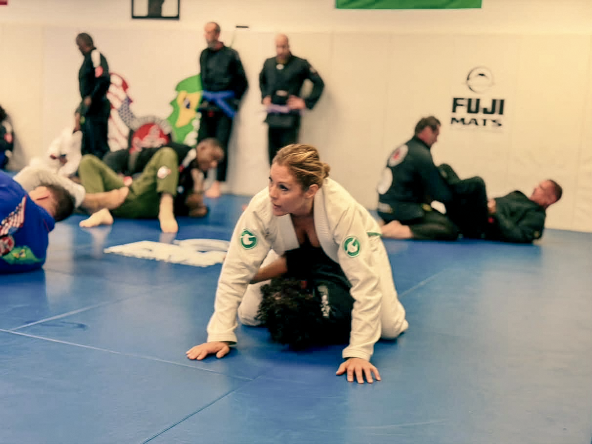 An adult woman practices control during a gi training round at the Academy