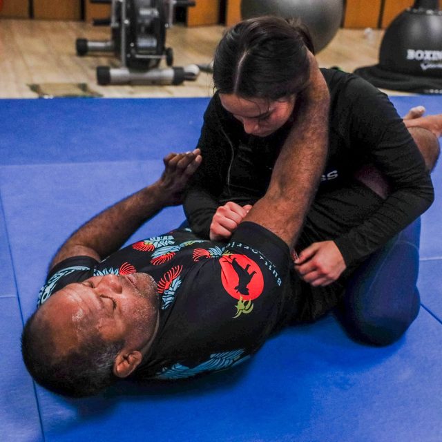 A student drives into top position on her training partner during a no-gi drill