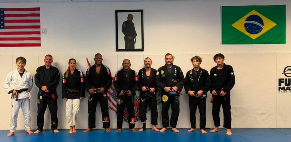 Black belts line up at the front of the Academy beneath the flags