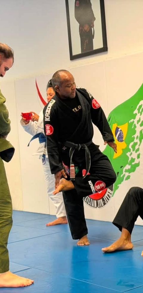 A black belt demonstrates a technique on a student while the class watches